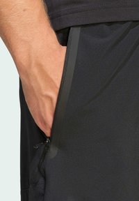 Shorts atléticos negros con un bolsillo lateral con cremallera. Tejido suave y ligero con un ligero brillo y un diseño ajustado para mayor comodidad.