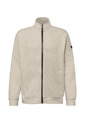 Jasno beżowa bluza na zamek z wysokim kołnierzem, długimi rękawami, dwoma bocznymi kieszeniami oraz czarnym zamkiem błyskawicznym biegnącym przez środek przodu.