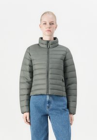 Giacca leggera a pompa cropped in verde tenue, con motivo a righe orizzontali, colletto alto e chiusura con zip completa.