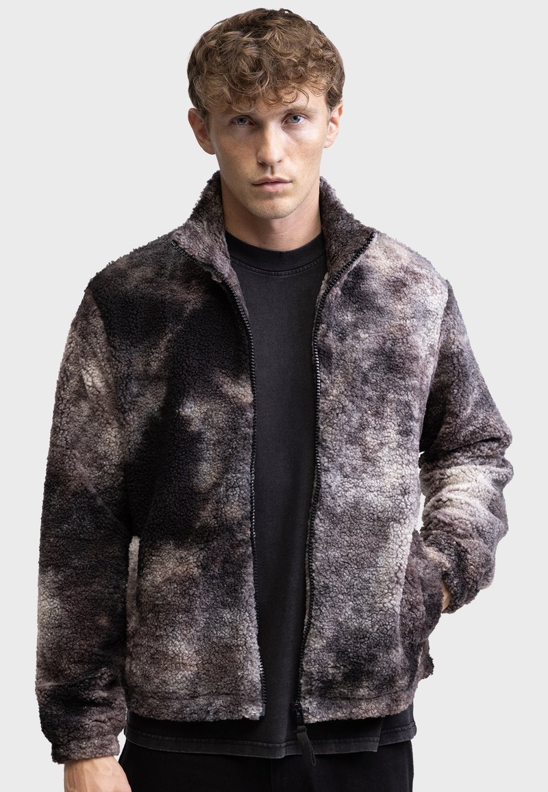 Strukturierte Fleecejacke mit durchgehendem Reißverschluss, hohem Kragen und einer Kombination aus grauen und schwarzen abstrakten Mustern. Geeignet für die Freizeit.