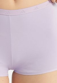 Lilac seamless shorts with a stretchy waistband featuring subtle brand markings. The fabric appears smooth and lightweight.