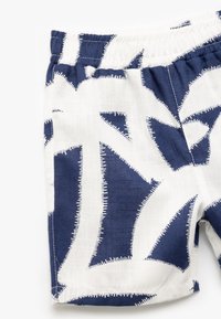 Bomuldsshorts med et navyblåt og hvidt mønster, der har abstrakte former og en syet kant langs kanterne. Elastisk talje.
