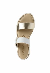 Sandal aperta con una striscia metallica dorata e una cinghia alla caviglia bianca regolabile. Suola piatta con rivestimento interno beige e design minimalista.