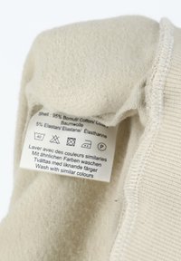 Etichetta in tessuto beige con istruzioni per la cura, composta dal 95% di cotone e dal 5% di elastan, con una trama morbida e cuciture visibili.