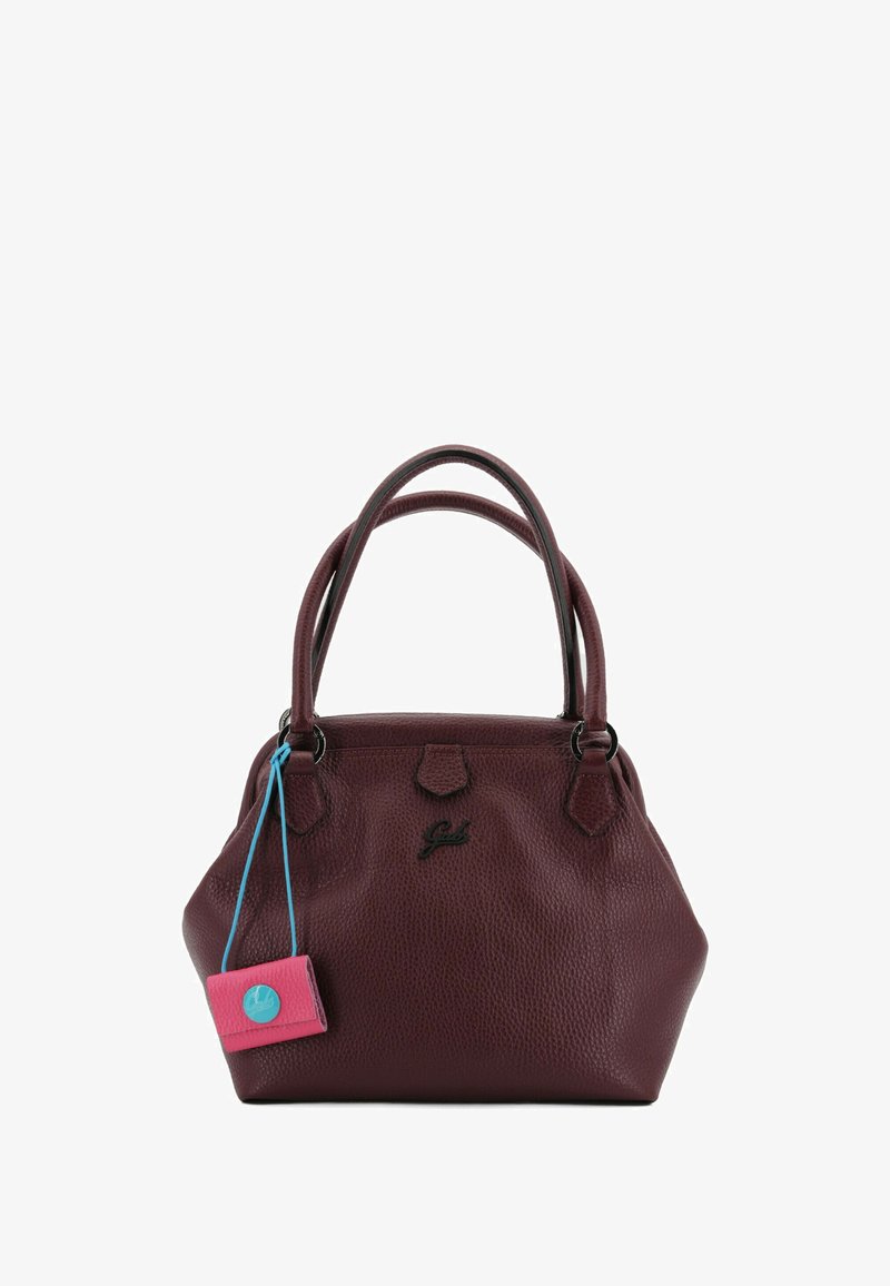Borsa a mano in pelle bordeaux con doppio manico, superficie strutturata, dettagli in metallo e una targhetta rosa con particolare blu applicata.