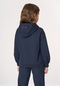 Felpa con cappuccio blu navy con polsini e orlo a coste. Presenta la scritta ricamata "U.S. Polo Assn." sul retro del cappuccio.