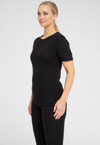 Sort t-shirt med kortærmer lavet af blødt stof, med rund halsudskæring og tætsiddende silhuet, parret med matchende sorte bukser.