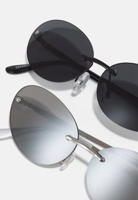 Ochelari de soare rotunzi cu lentile negre și gri degrade, rame metalice și suporturi pentru nas din silicon transparent. Design simplu cu un minim de accesorii.