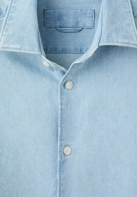 Lyseblå denimskjorte med klassisk krave, knaplukning og blød tekstur med diskrete syningsdetaljer.