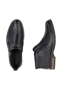 Bottines en cuir noir avec fermeture éclair latérale et bordure de semelle marron, l’une vue de dessus, l’autre de côté.