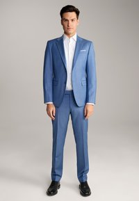 Helles blaues Anzug mit Reverskragen, einreihigem Knopfverschluss und passender Hose. Kombiniert mit einem weißen Dresshemd und schwarzen Schuhen.