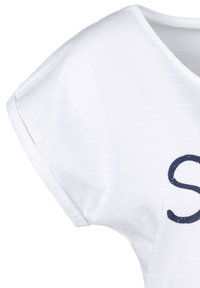Camisa blanca de manga corta con un diseño de cuello en V y letras azul oscuro en la parte delantera. La tela tiene una ligera textura con fibras visibles.