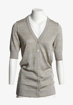 Beżowy krótki sweter na guziki z dwoma kieszeniami z przodu i ściągaczami na rękawach na białym torsie manekina.