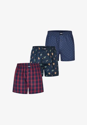 Three pairs of men's boxer shorts with elastic waists: navy with gingerbread and candy cane print, blue with small dot pattern, and red plaid.
