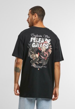 Black oversized t-shirt featuring colorful rooster graphics and white text on the back. Short sleeves, cotton material, relaxed fit.