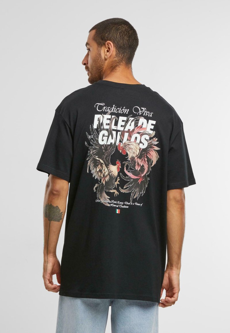 Černé oversized tričko s barevnými grafikami kohouta a bílým textem na zádech. Krátké rukávy, bavlněný materiál, uvolněný střih.