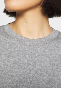Grå bomulds t-shirt med rund halsudskæring og korte ærmer, der har en blød tekstur og let sprinkles i stoffet.