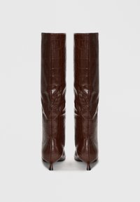 Bottes marron jusqu'aux genoux avec une finition en cuir gaufré crocodile brillant et des talons fins et pointus. Présente une texture douce et froncée au niveau du tige.