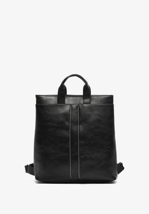 Mochila de cuero negro con dos asas en la parte superior, superficie texturizada, una línea vertical de tachuelas plateadas y una correa de hombro ajustable.