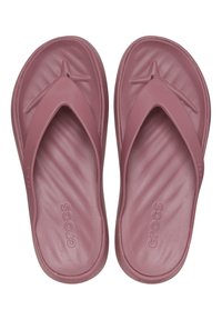 Chanclas rosas hechas de goma blanda con una suela estriada. Presentan un diseño de tira en forma de V y el logo "Crocs" en el lateral.