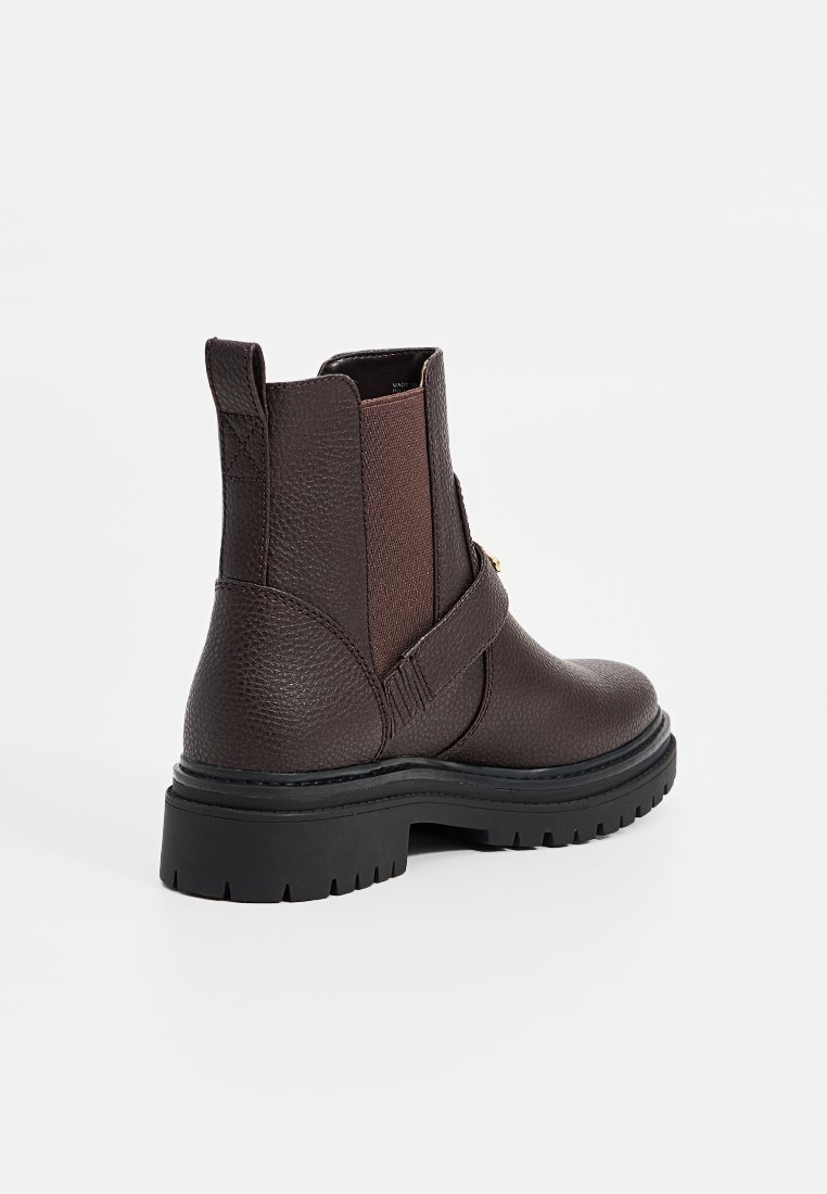 Botín de cuero marrón hasta el tobillo con paneles laterales elásticos, acabado texturizado, detalle de correa y suela de goma gruesa.