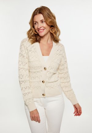 Cardigan beige chiaro con un motivo a maglia testurizzato, caratterizzato da un profondo scollo a V, maniche lunghe e tre grandi bottoni in legno.