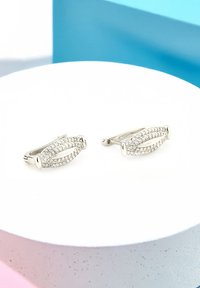 Silverörhängen med oval design som har klara rhinestones i pavéinställning, vilket visar en slät yta och säker låsning.