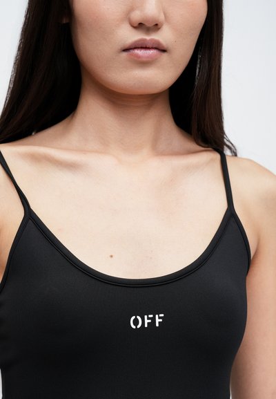 Top negru din bumbac cu striații, cu bretele subțiri, având un logo alb imprimat "OFF" pe piept. Textură netedă și design ajustat.