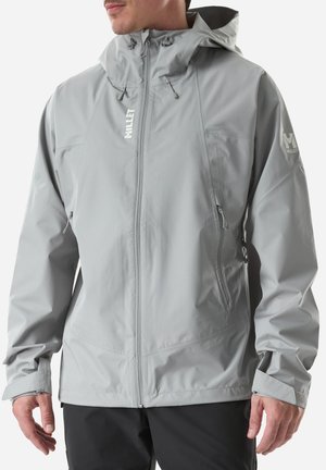 Man wearing light gray hooded waterproof jacket with front zipper and zippered side pockets, standing against white background.