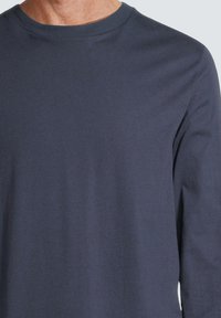 T-shirt en coton bleu marine à manches longues avec un col rond. Texture douce et finition lisse. Aucune motif ou graphique visible.