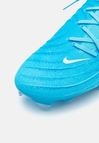 Scarpa da calcio azzurro chiaro con tomaia testurizzata e strisce verticali, logo bianco e tacchetti trasparenti sulla suola per una migliore aderenza.