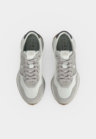Paire de baskets Hogan blanches et grises avec lacets, vue de dessus sur un fond uni clair.