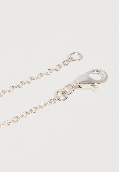 Stříbrný řetízek s karabinkou a malým kulatým zapínáním na světlém pozadí.