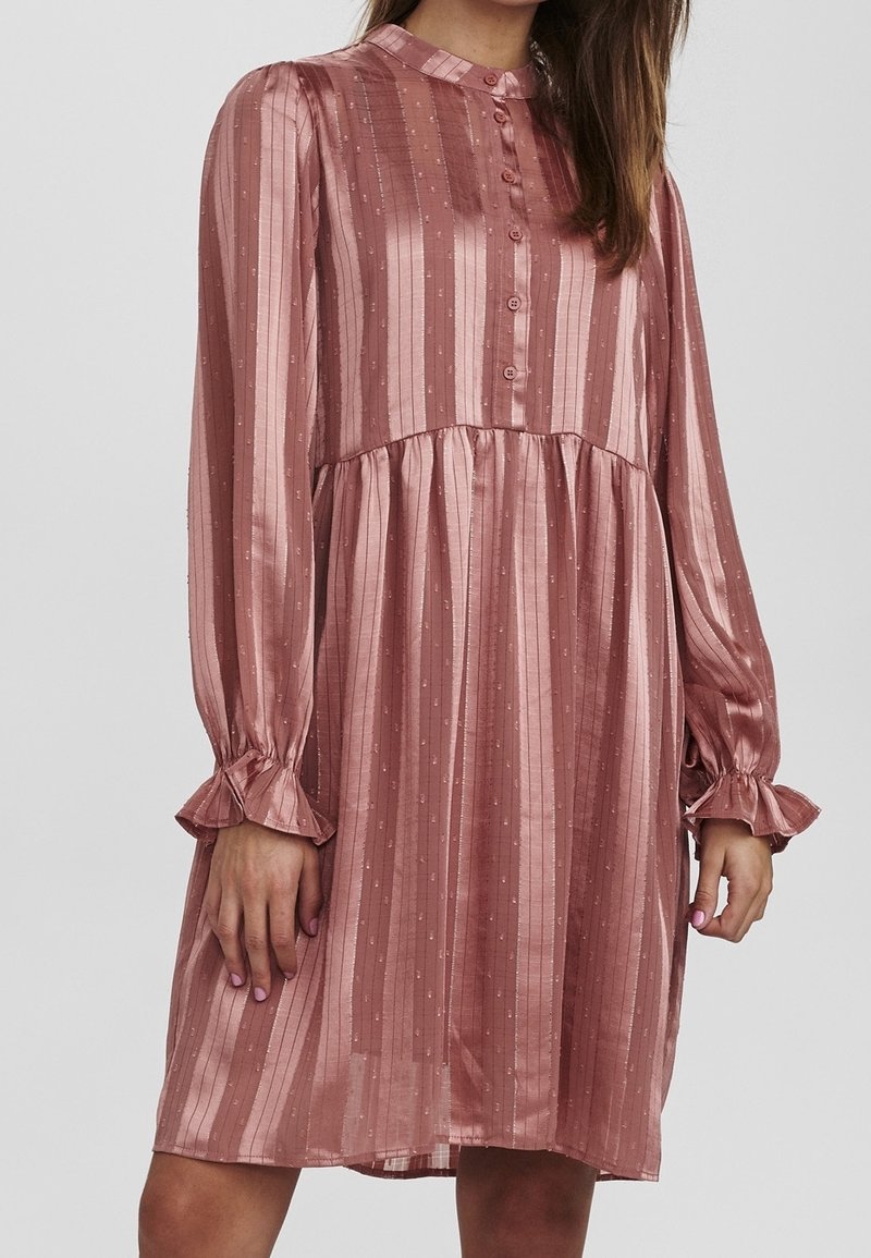 Rosenpinkes Satin-Kleid mit vertikalen Streifen, durchgeknöpftem Vorderteil und gerafften Manschetten. Es weist subtile Punktmuster und eine ausgestellte Silhouette auf.