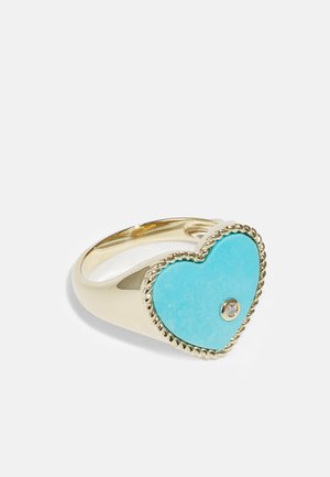 Gold ring featuring a large heart-shaped turquoise stone with a textured, twisted rope accent. Includes a small clear gemstone in the center.