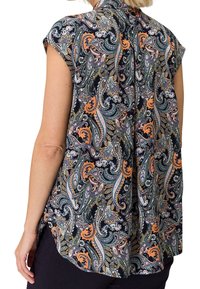 Femme portant un haut sans manches avec un motif paisley coloré en marine, orange, vert et blanc, vue de dos.