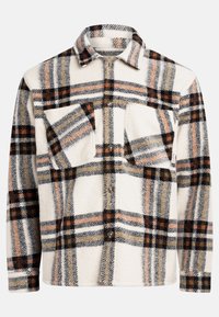 Chemise en flanelle blanche avec un motif à carreaux comportant des lignes noires, orange et brunes. Fermeture à boutons sur le devant avec deux poches poitrine. Texture douce.