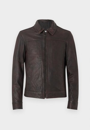 Σκούρο καφέ δερμάτινο μπουφάν με φερμουάρ μπροστά, τζιράκι, μυτερό γιακά και μακριά μανίκια, εμφανιζόμενο μπροστά σε απλό ανοιχτό φόντο.