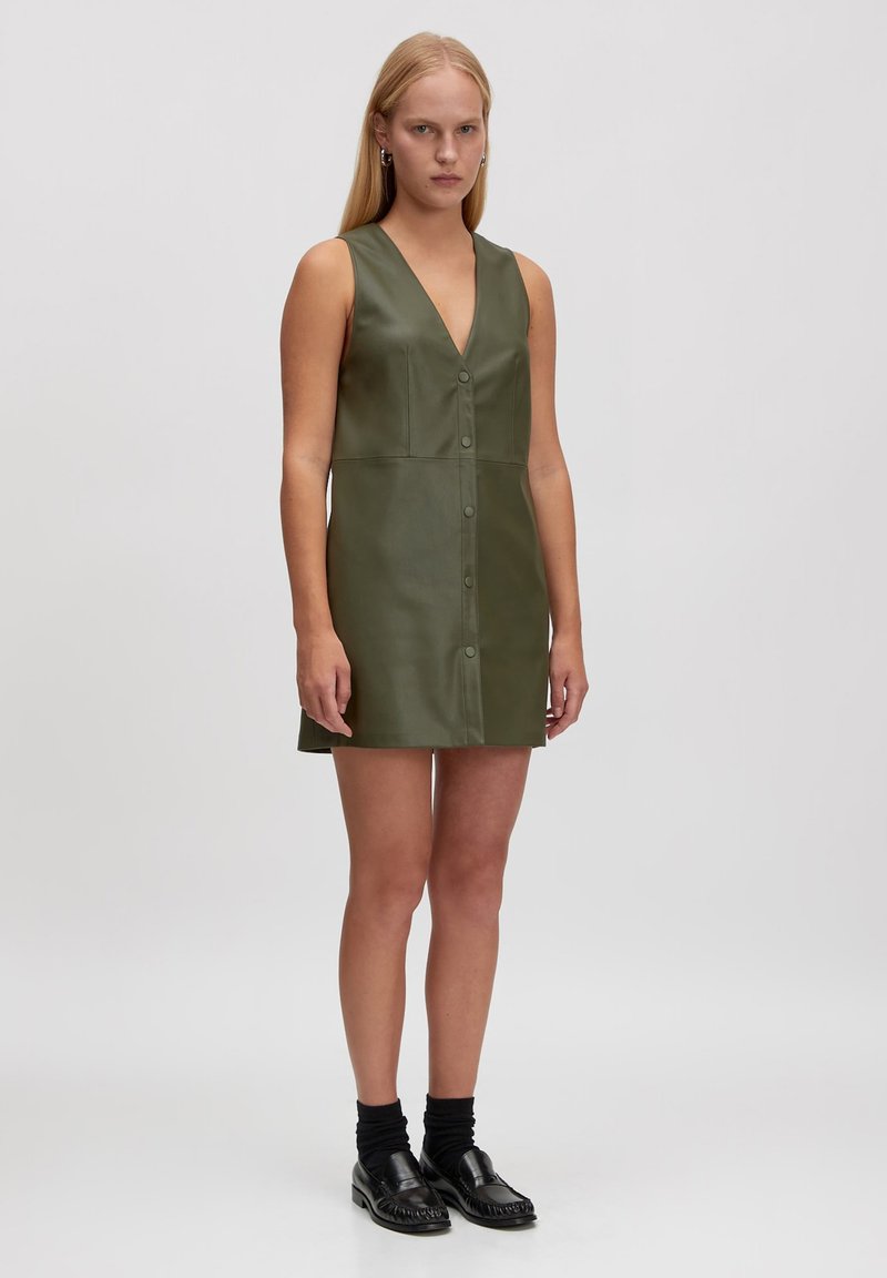 Grünes Lederkleid ohne Ärmel mit V-Ausschnitt, vorderer Knopfverschluss und leichtem A-Linien-Schnitt. Glatte Textur und minimalistisches Design.
