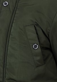 Giacca padded verde scuro con tasca con zip e chiusura a bottone nero, caratterizzata da un motivo in tessuto strutturato.