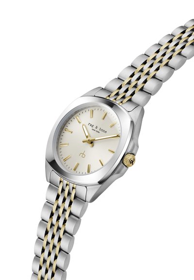 Sølvfarvet ur med en rund hvid urskive, guld accenter og et tofarvet metalarmbånd med rustfrit stål og guldled.