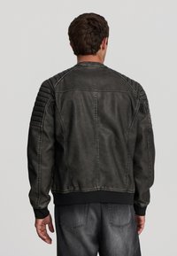 Giacca in pelle grigia scura da uomo con spalle a coste e maniche testurizzate, caratterizzata da una chiusura con zip e polsini ed orlo elasticizzati.