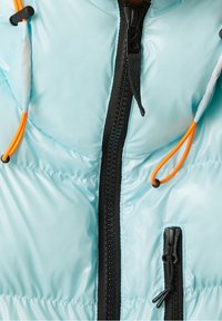 Světle modrá péřová bunda s černým zipem a oranžovými stahovacími šňůrkami, s prošívanou texturou a malou boční kapsou na zip.