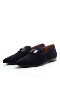 Granatowe zamszowe buty slip-on z wydłużonym noskiem, z metalową srebrną taśmą oraz minimalnymi detalami stębnowania. Płaska podeszwa.
