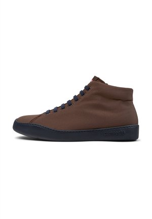 Brown canvas high-top sneaker with navy accents, round toe, and textured surface. Features dark rubber sole and blue laces. Brand logo on side.