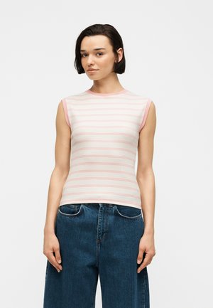 Νεαρή γυναίκα που φοράει αμάνικο τοπ με ανοιχτό ροζ και λευκές ρίγες, συνδυασμένο με ψηλόμεσο μπλε τζιν, σε απλό φόντο.