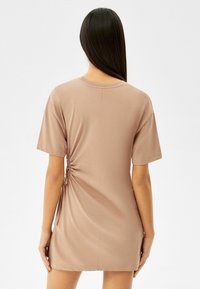 Brązowa sukienka z krótkim rękawem z marszczonym bocznym detalem, wykonana z miękkiej tkaniny, z okrągłym dekoltem i luźnym krojem.