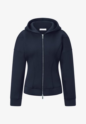 Námořnická mikina s kapucí a zipem, která se vyznačuje splývavým střihem, předním zipem, žebrovanými manžetami a plochými švy pro strukturované detaily.