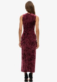 Mauve fluwelen maxi-jurk met een getailleerd silhouet en mouwloos ontwerp. Beschikt over een gladde textuur en een discrete ritssluiting aan de achterkant.