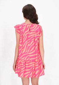 Kurzärmliges Kleid aus pinkem Stoff mit einem kontrastierenden Pfirsich-Zickzackmuster, Rüschenschultern und einem gestuften Rüschensaum. Knopfdetails am Rücken.